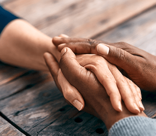 An individuals hand is being embraced by the hands of another person